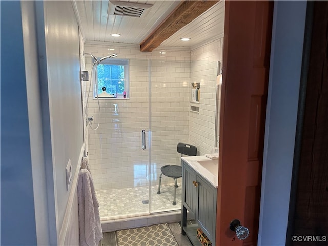 bathroom featuring a shower with door, beam ceiling, and vanity