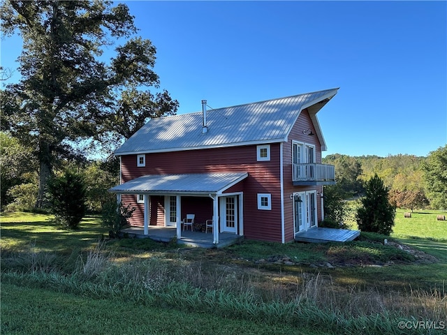 back of property with a balcony, a lawn, and a patio