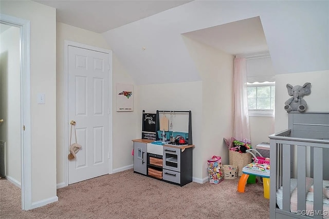 bedroom featuring a crib, light colored carpet, and lofted ceiling