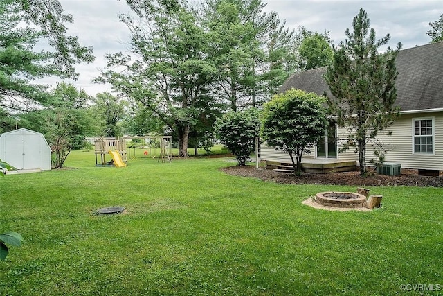 view of yard featuring a playground, a storage shed, a fire pit, and central AC unit