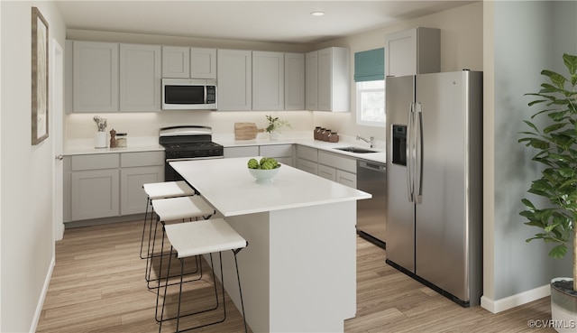 kitchen featuring a kitchen breakfast bar, light wood-type flooring, stainless steel appliances, sink, and a center island