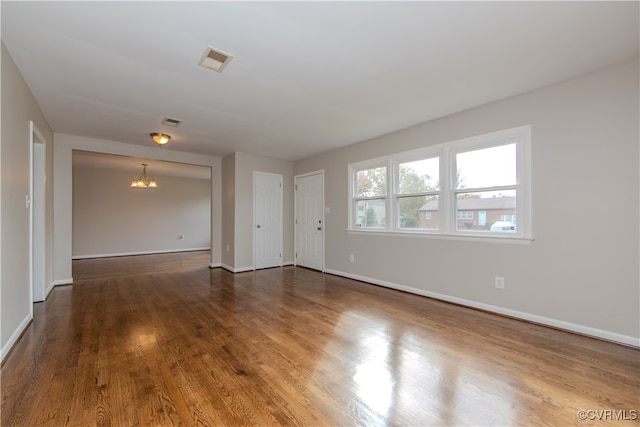 unfurnished room with wood-type flooring and a notable chandelier