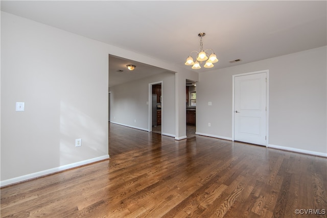 unfurnished room with an inviting chandelier and dark hardwood / wood-style floors