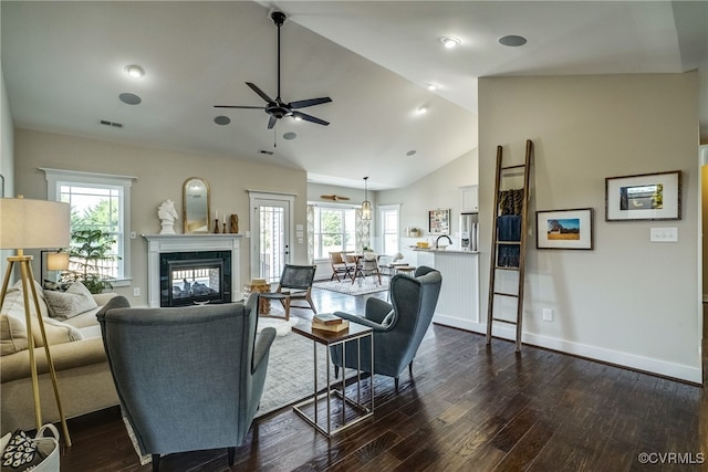 living room featuring a fireplace, dark wood-type flooring, high vaulted ceiling, and a wealth of natural light