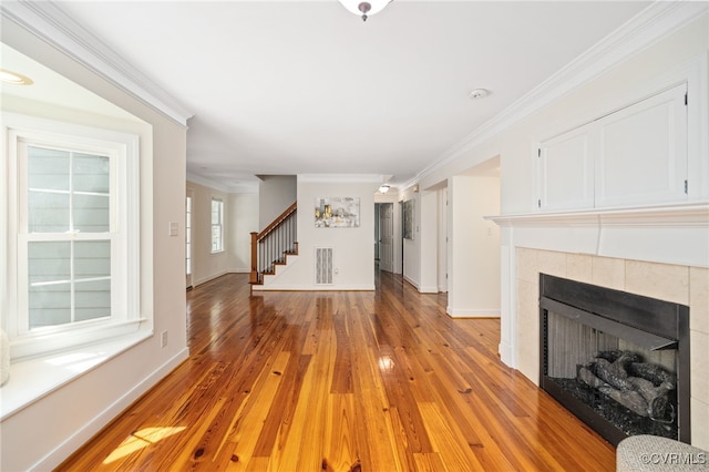 unfurnished living room featuring light hardwood / wood-style floors, crown molding, and a tile fireplace