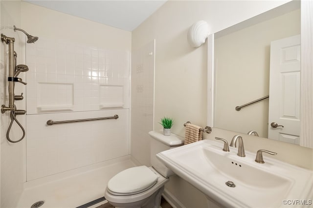 bathroom featuring sink, toilet, and tiled shower