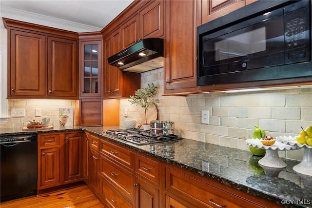 kitchen with light hardwood / wood-style floors, dark stone counters, decorative backsplash, ornamental molding, and black appliances