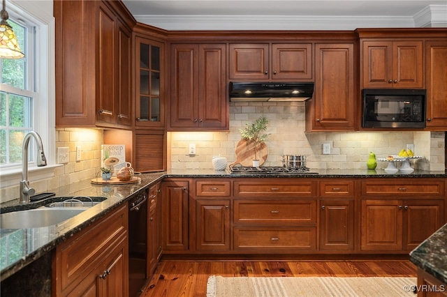 kitchen with dark stone countertops, light hardwood / wood-style floors, black appliances, and sink