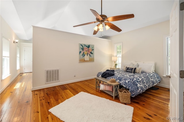 bedroom with ceiling fan, wood-type flooring, lofted ceiling, and multiple windows