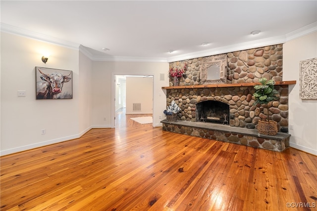 unfurnished living room featuring ornamental molding, a stone fireplace, and wood-type flooring