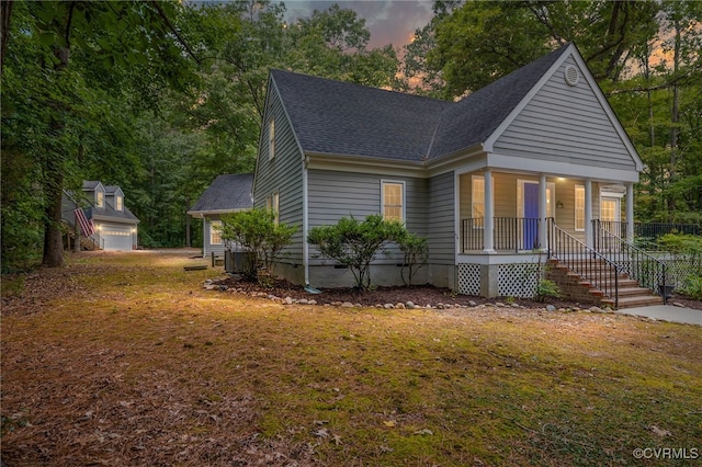 view of front of house with covered porch, a lawn, and a garage