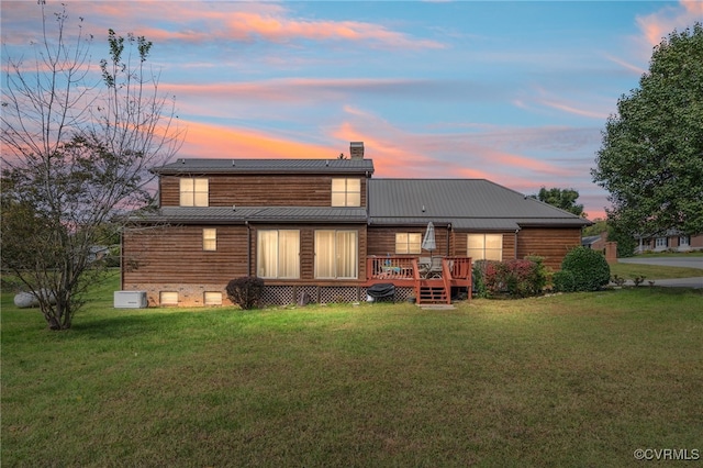 back house at dusk featuring a deck and a yard