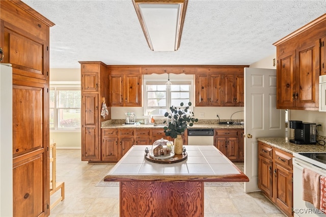 kitchen featuring tile countertops, a textured ceiling, light tile patterned flooring, a center island, and white appliances