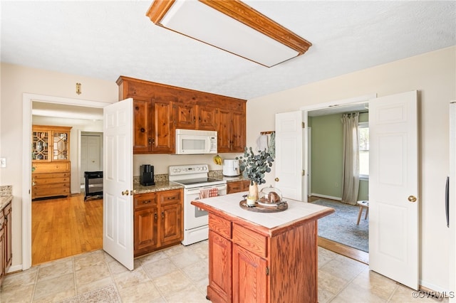 kitchen with white appliances, light hardwood / wood-style flooring, a textured ceiling, and a center island