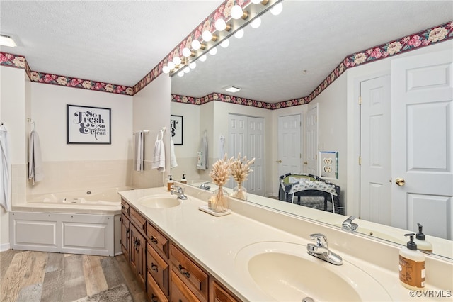 bathroom with vanity, a textured ceiling, hardwood / wood-style flooring, and a tub to relax in