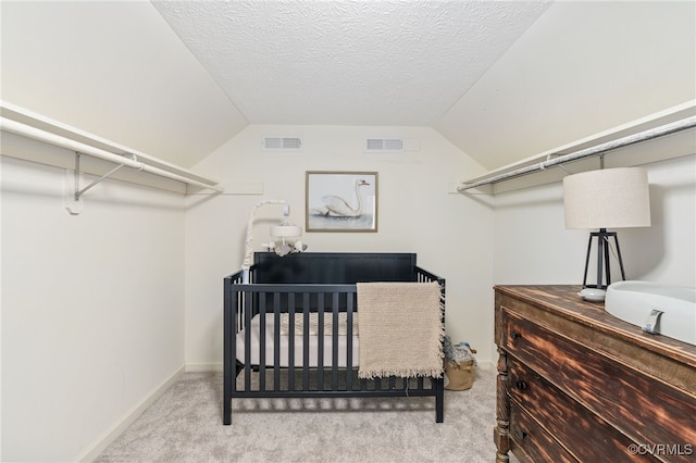 bedroom featuring lofted ceiling, light carpet, and a crib