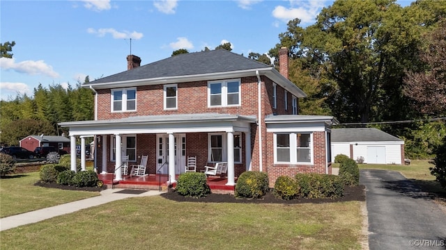 colonial-style house featuring an outdoor structure, a front lawn, covered porch, and a garage