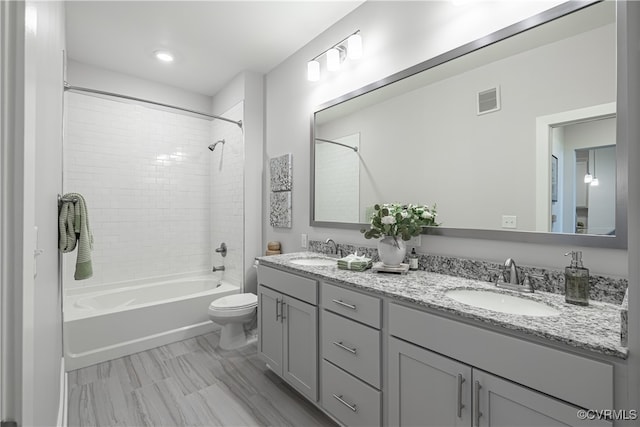 full bathroom featuring tiled shower / bath, vanity, and toilet