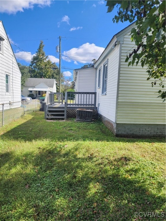 view of yard with central air condition unit and a deck