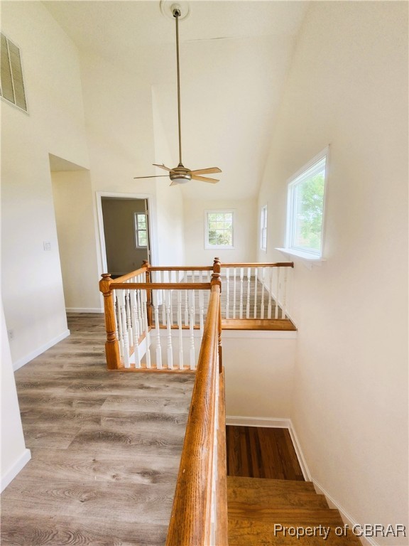 staircase with hardwood / wood-style flooring, high vaulted ceiling, and ceiling fan