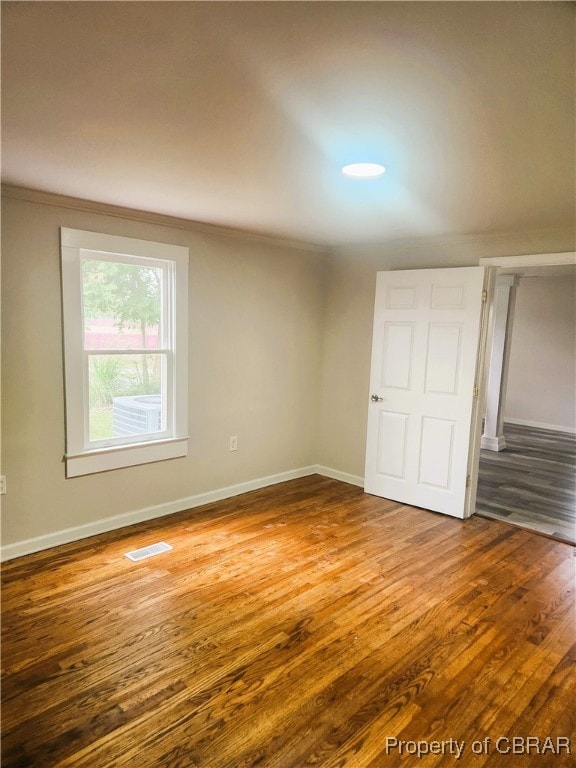 empty room with ornamental molding and hardwood / wood-style floors