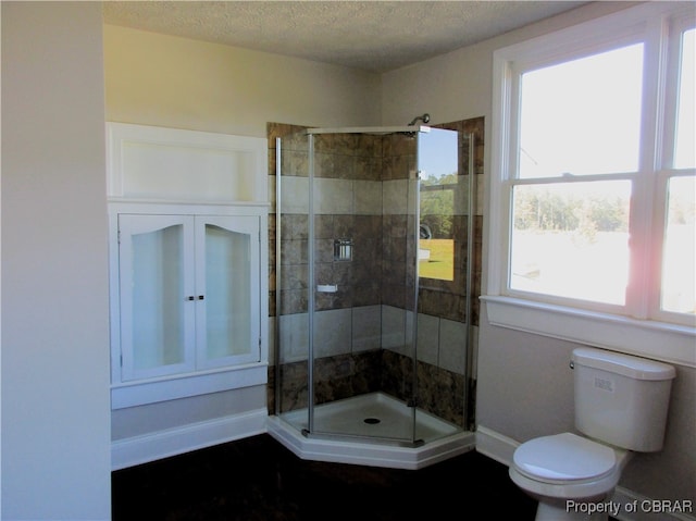 bathroom featuring an enclosed shower, toilet, and a textured ceiling