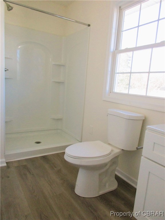 bathroom with a shower, a wealth of natural light, wood-type flooring, and toilet