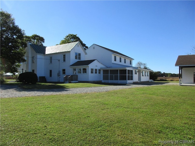 rear view of property featuring a sunroom and a lawn