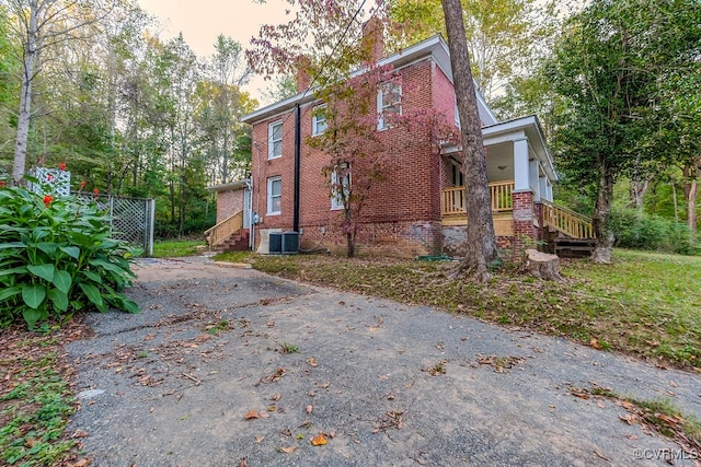 property exterior at dusk with cooling unit and covered porch