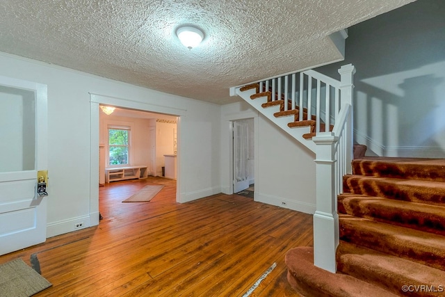 stairway with wood-type flooring and a textured ceiling