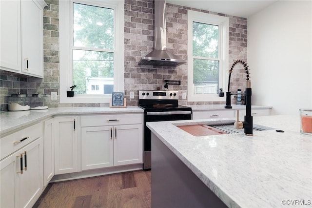 kitchen featuring sink, wall chimney range hood, stainless steel range with electric cooktop, and light stone counters