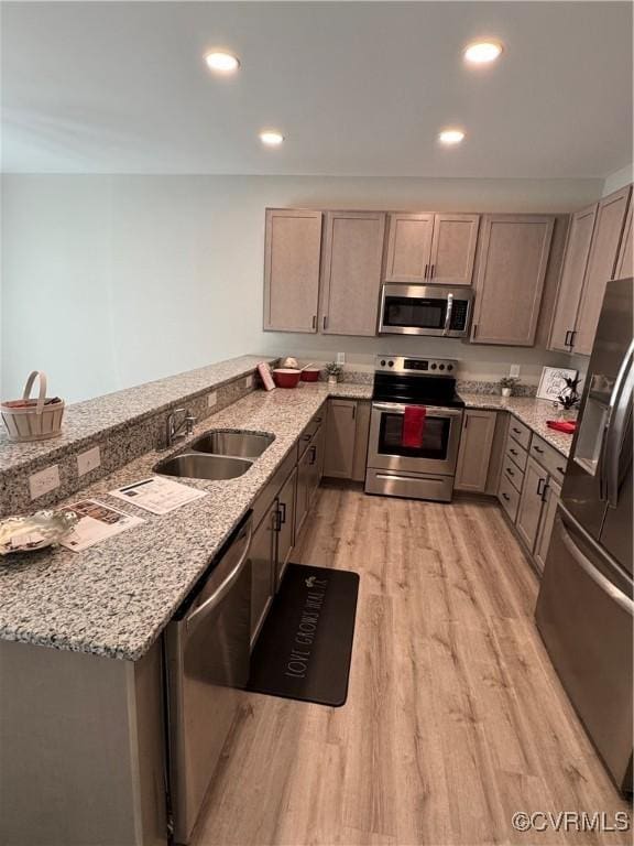 kitchen featuring appliances with stainless steel finishes, sink, light stone counters, and light hardwood / wood-style floors