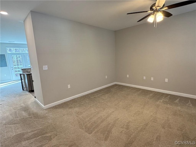 spare room featuring carpet floors, baseboards, and a ceiling fan