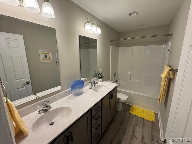 full bath featuring double vanity, toilet, a sink, and wood finished floors