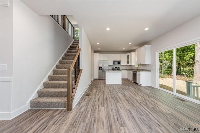 kitchen with sink, light hardwood / wood-style flooring, appliances with stainless steel finishes, a center island, and white cabinets