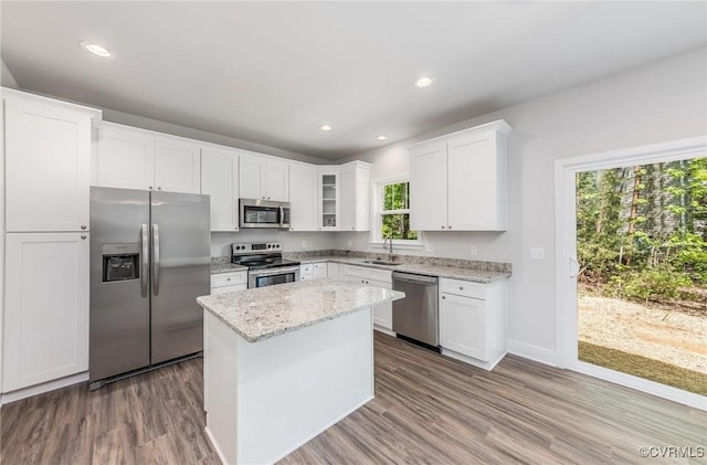 kitchen featuring a kitchen island, sink, white cabinets, light stone counters, and stainless steel appliances