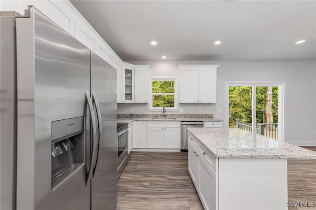 kitchen with sink, light stone counters, white cabinetry, a center island, and stainless steel appliances