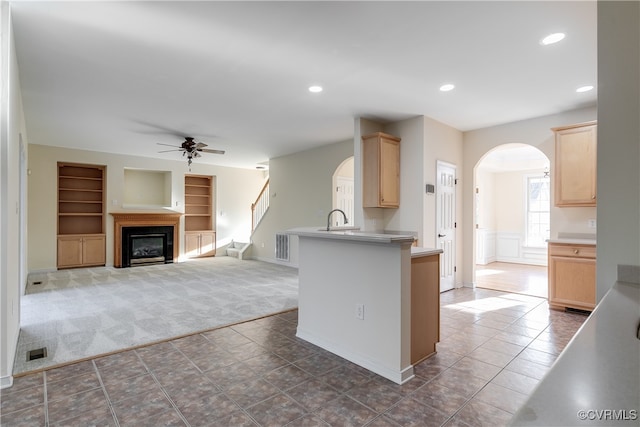 kitchen with kitchen peninsula, built in shelves, ceiling fan, and light brown cabinets