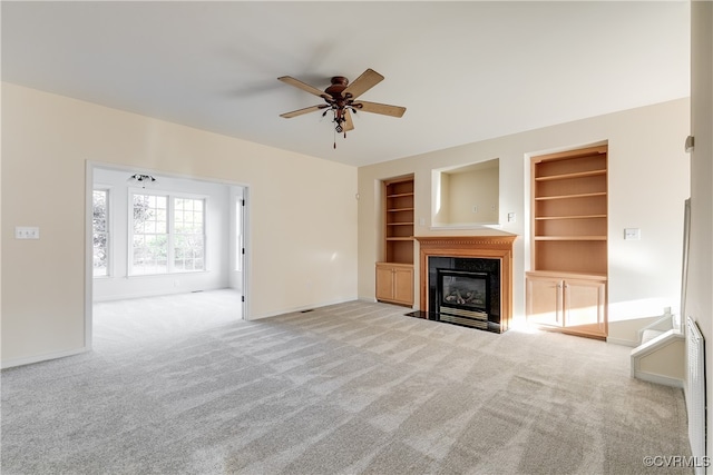 unfurnished living room featuring ceiling fan, built in features, and light carpet