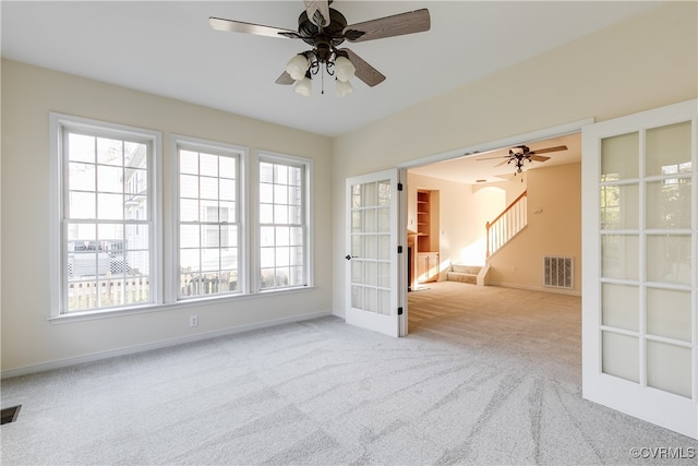 carpeted empty room featuring ceiling fan, french doors, and a healthy amount of sunlight