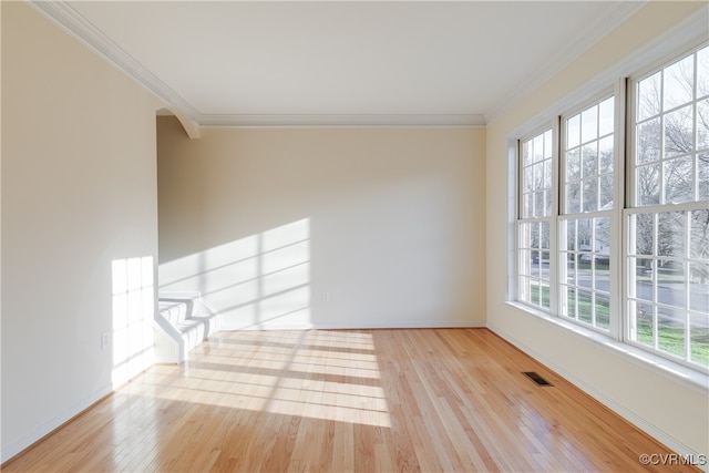 unfurnished room with crown molding, a wealth of natural light, and light hardwood / wood-style flooring