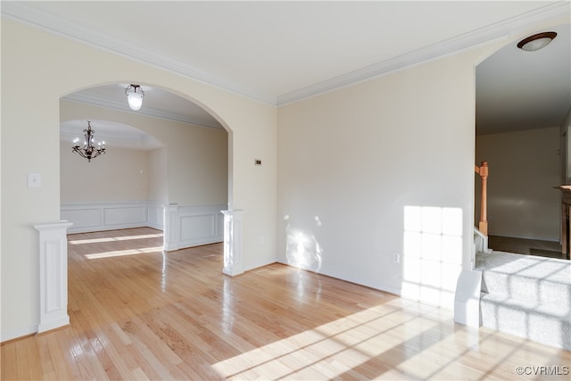 unfurnished room with an inviting chandelier, ornamental molding, and light hardwood / wood-style flooring