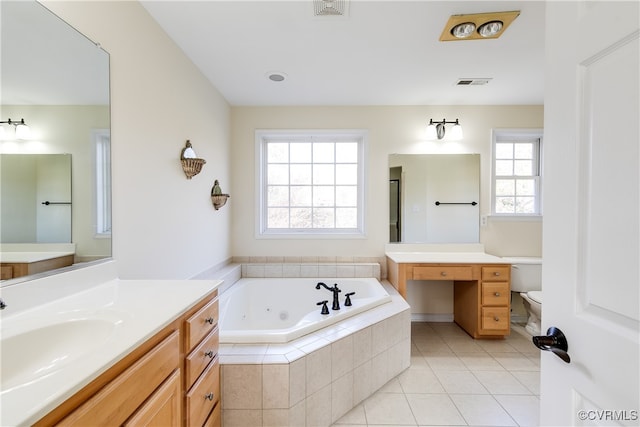 bathroom featuring tile patterned floors, toilet, plenty of natural light, and tiled tub