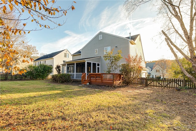 back of house with a sunroom, a wooden deck, and a lawn