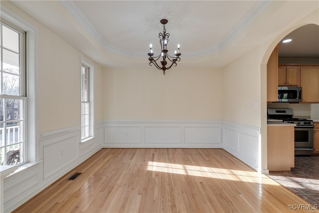 unfurnished dining area featuring a raised ceiling, light hardwood / wood-style flooring, and a notable chandelier