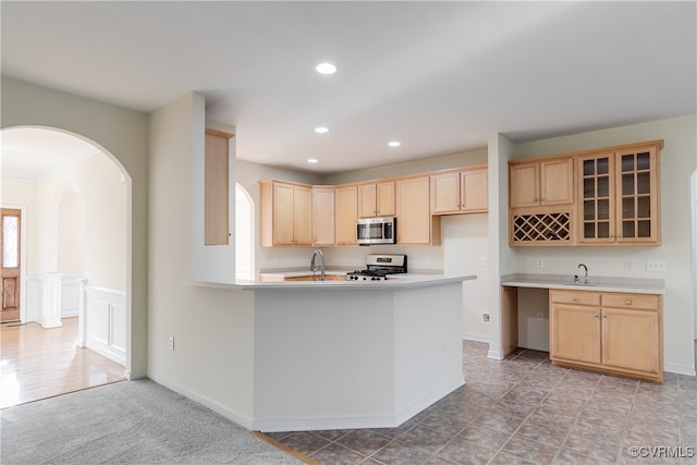 kitchen featuring light brown cabinetry, sink, and range