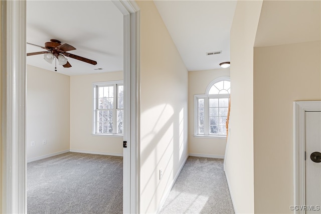 hallway featuring plenty of natural light and light colored carpet