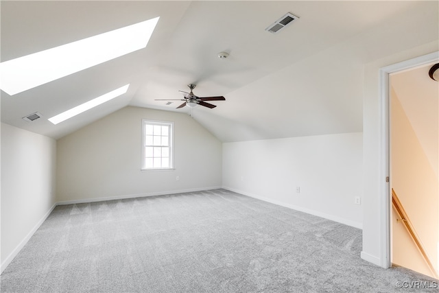 additional living space with light carpet, lofted ceiling with skylight, and ceiling fan