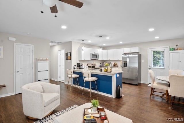 kitchen with dark wood-type flooring, appliances with stainless steel finishes, hanging light fixtures, and white cabinetry