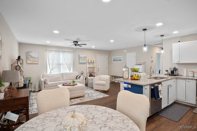 kitchen with white cabinets, dark hardwood / wood-style flooring, stainless steel dishwasher, decorative light fixtures, and sink